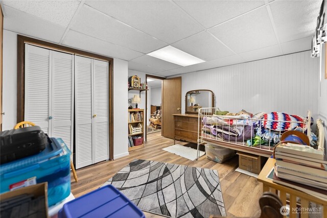 bedroom with a closet, a drop ceiling, and wood finished floors