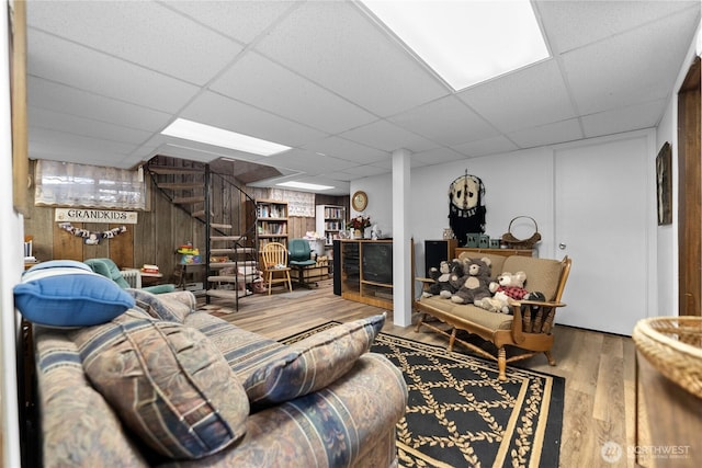 living area featuring a drop ceiling, wood finished floors, and wooden walls