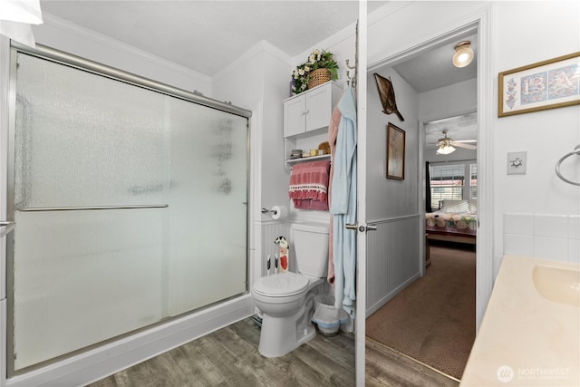 bathroom with ensuite bathroom, toilet, a wainscoted wall, wood finished floors, and a stall shower