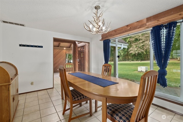 dining room featuring an inviting chandelier, light tile patterned floors, and a textured ceiling