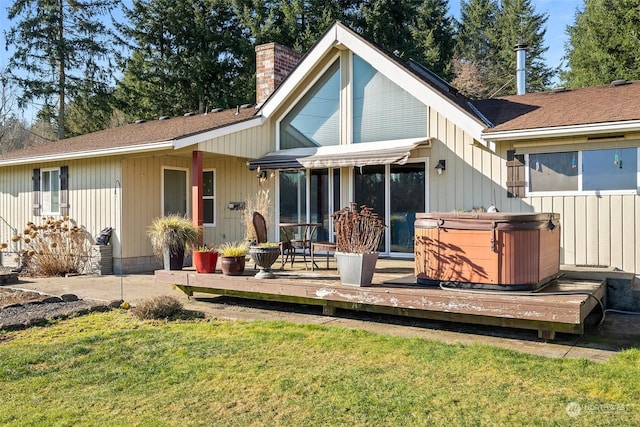 rear view of house with a wooden deck, a yard, and a hot tub