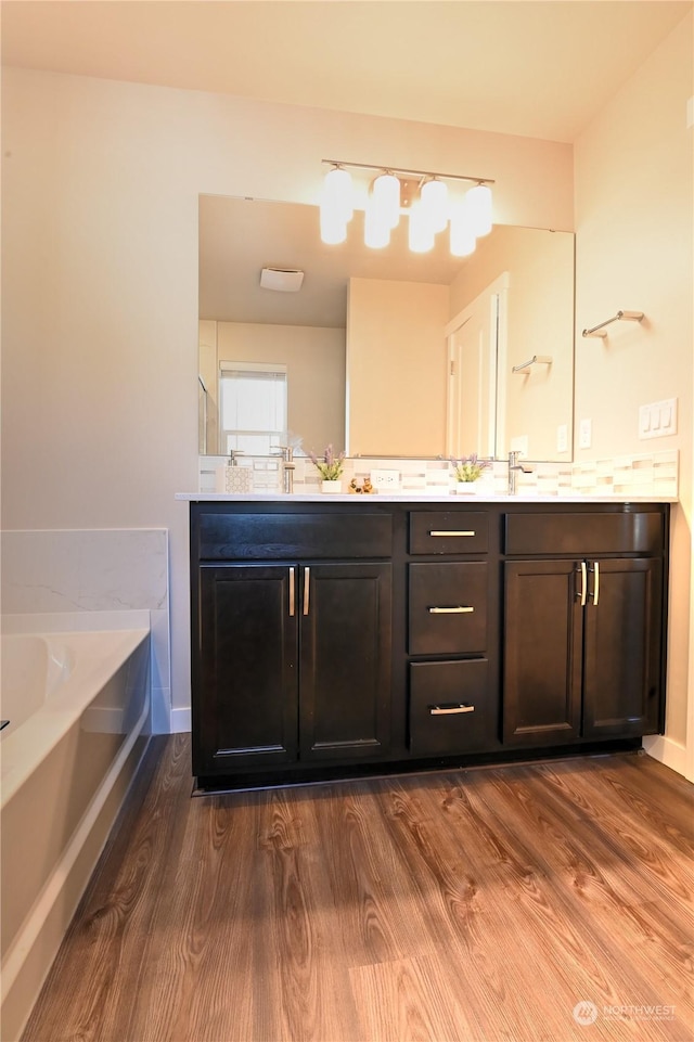 bathroom with vanity, a bath, and wood-type flooring