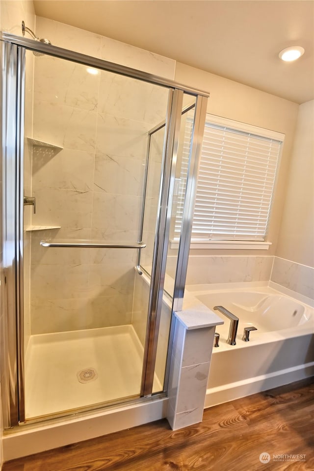 bathroom featuring plus walk in shower and hardwood / wood-style floors