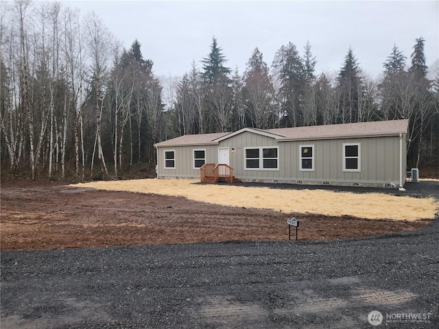 manufactured / mobile home featuring crawl space, a view of trees, and roof with shingles