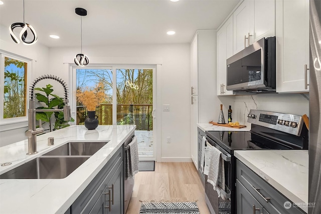 kitchen with appliances with stainless steel finishes, sink, hanging light fixtures, and white cabinets