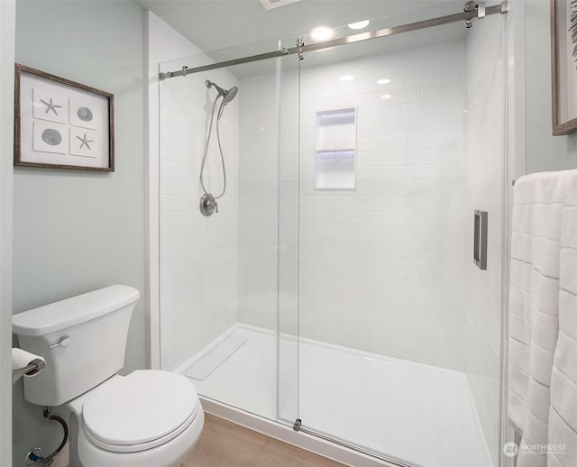 bathroom with an enclosed shower, hardwood / wood-style flooring, and toilet