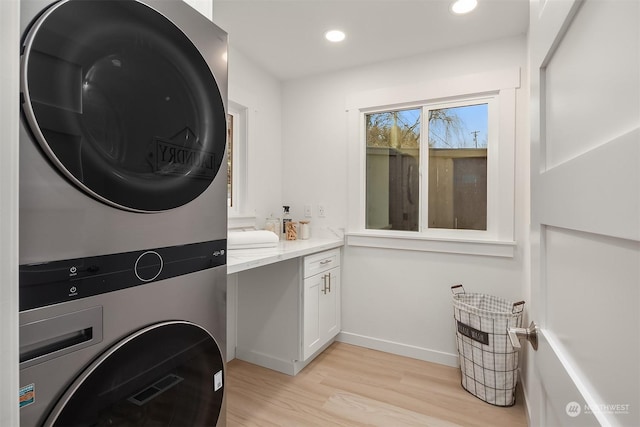 clothes washing area with stacked washer / drying machine and light hardwood / wood-style flooring