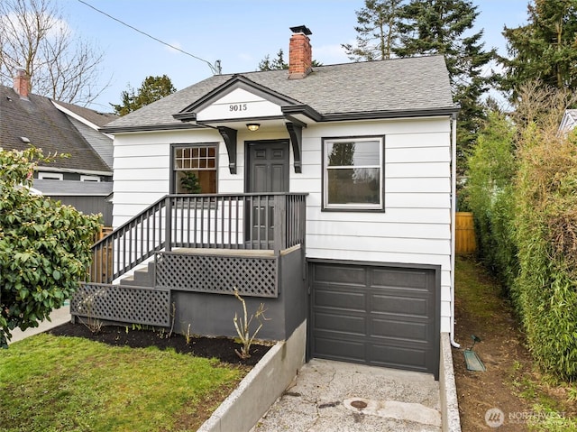 view of front of house with a shingled roof, fence, a garage, and a chimney