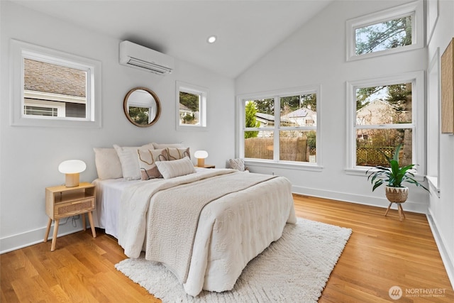 bedroom with light wood-style flooring, baseboards, a wall mounted AC, and lofted ceiling