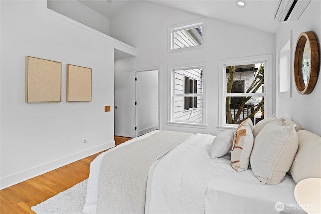 bedroom featuring high vaulted ceiling, wood finished floors, a wall unit AC, recessed lighting, and baseboards