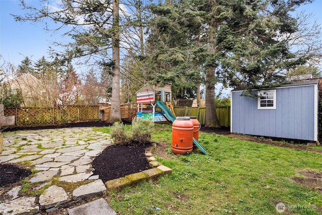 view of yard featuring an outbuilding, a fenced backyard, a storage shed, a playground, and a patio area