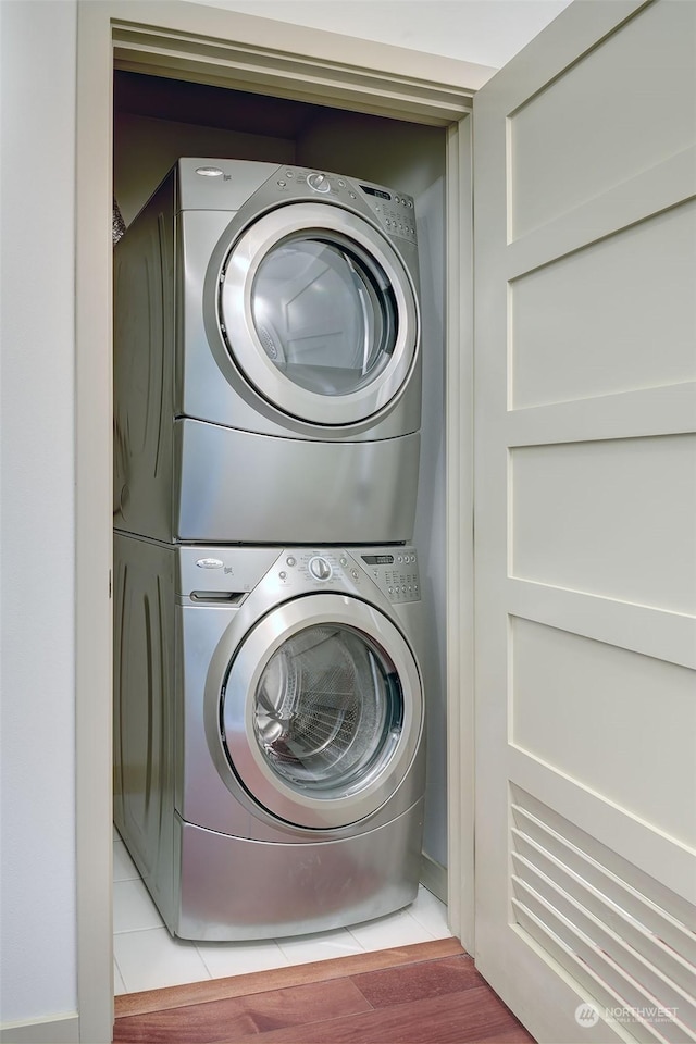 clothes washing area with stacked washer / dryer and light wood-type flooring