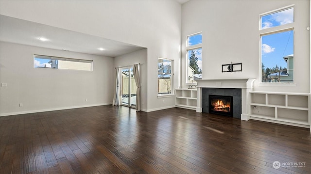 unfurnished living room featuring a towering ceiling and dark hardwood / wood-style flooring