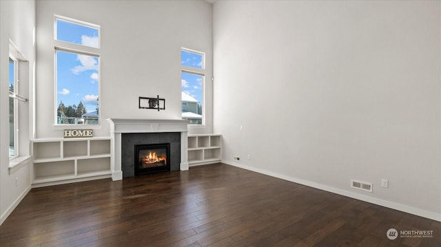 unfurnished living room featuring dark hardwood / wood-style flooring and a high ceiling