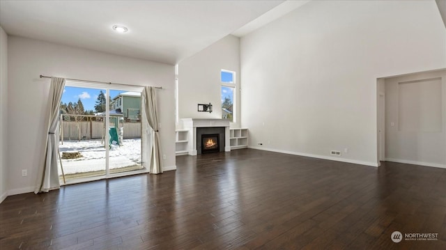 unfurnished living room with dark hardwood / wood-style floors and a towering ceiling