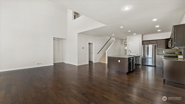 kitchen featuring sink, dark brown cabinets, stainless steel appliances, dark hardwood / wood-style floors, and an island with sink