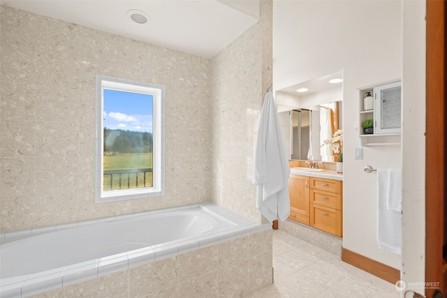 bathroom with a relaxing tiled tub, tile patterned floors, and vanity