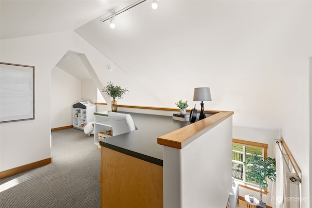 carpeted office space featuring vaulted ceiling and rail lighting