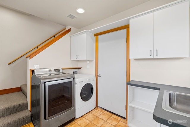 clothes washing area with independent washer and dryer, cabinets, and sink