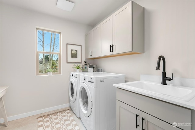 washroom with cabinets, washing machine and dryer, and sink