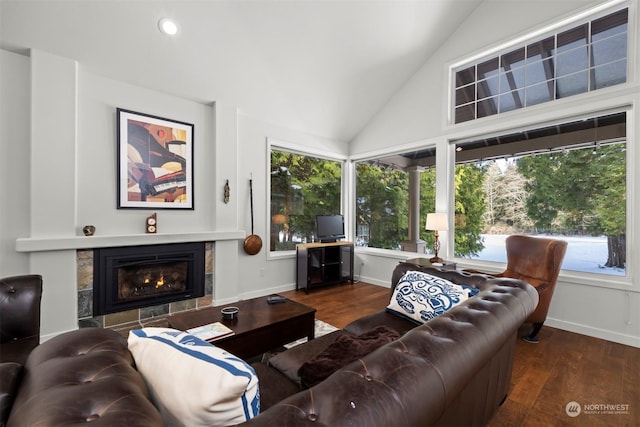 living room featuring plenty of natural light, dark hardwood / wood-style flooring, vaulted ceiling, and a tile fireplace