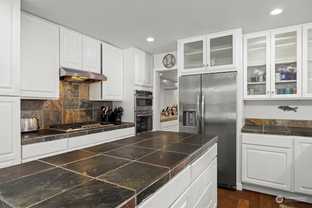 kitchen featuring stainless steel appliances, decorative backsplash, and white cabinets