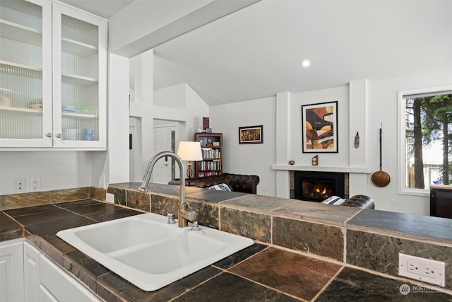 kitchen featuring vaulted ceiling, sink, and white cabinets