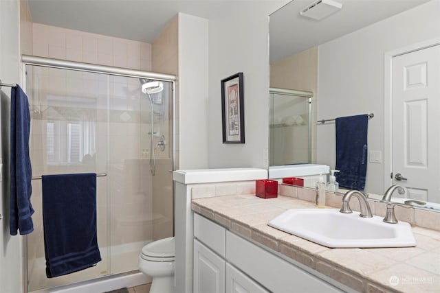 bathroom featuring vanity, a shower with shower door, and toilet