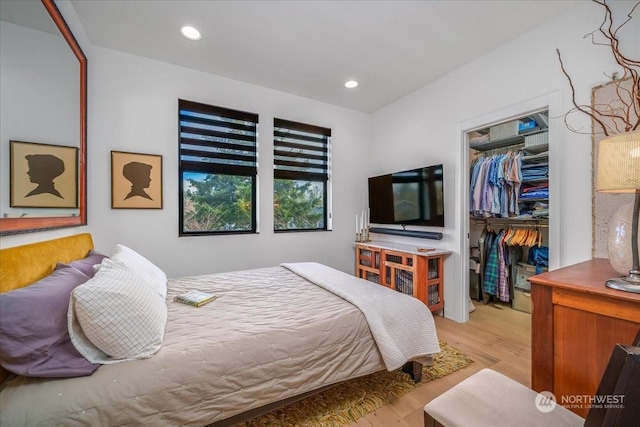 bedroom with a walk in closet, light hardwood / wood-style floors, and a closet