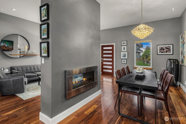 dining room featuring dark wood-type flooring, a multi sided fireplace, and a chandelier