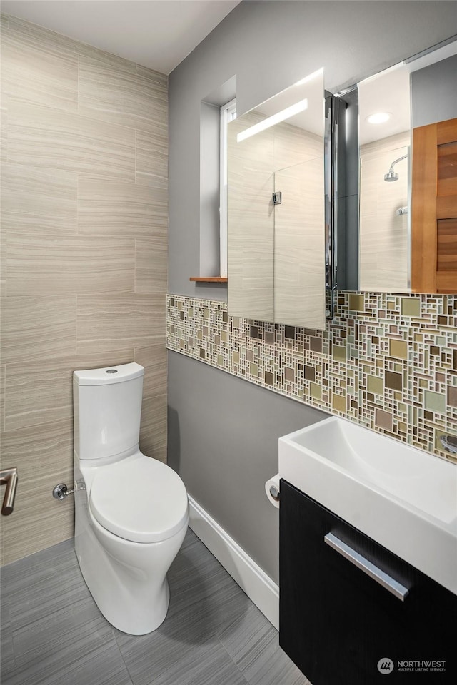 bathroom with tasteful backsplash, tile walls, tile patterned flooring, vanity, and toilet