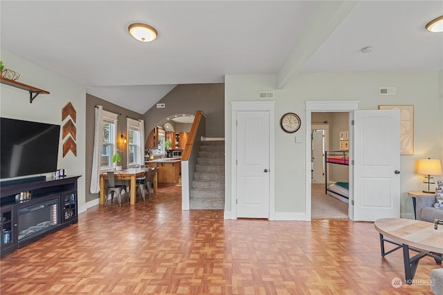 living room featuring light parquet flooring and vaulted ceiling with beams