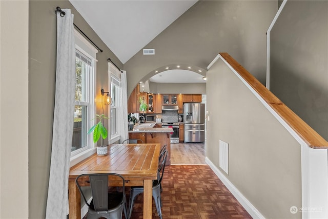 dining room featuring sink, dark parquet flooring, and vaulted ceiling