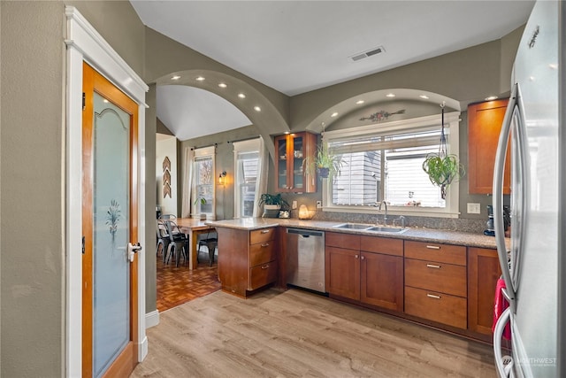 kitchen with appliances with stainless steel finishes, sink, light hardwood / wood-style floors, and kitchen peninsula