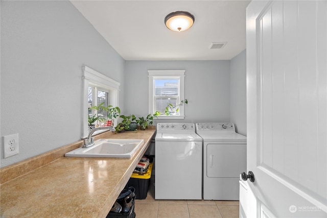 laundry area featuring separate washer and dryer, sink, and light tile patterned floors