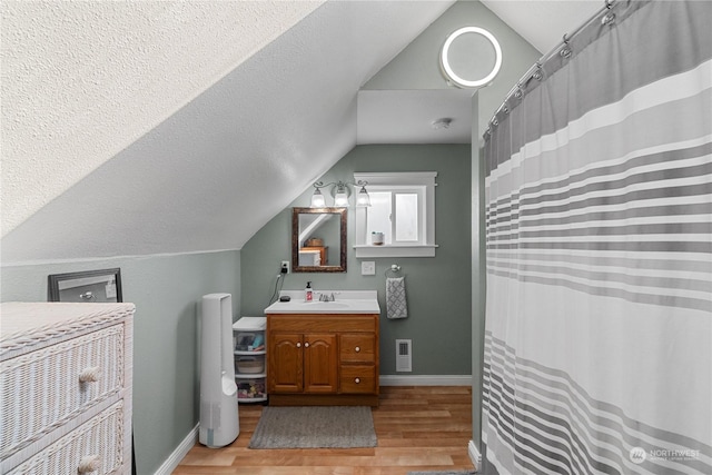 bathroom with lofted ceiling, wood-type flooring, vanity, and a textured ceiling