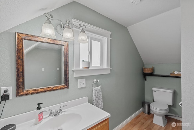 bathroom with hardwood / wood-style flooring, vaulted ceiling, vanity, and toilet