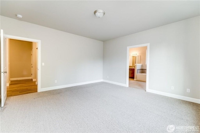 unfurnished bedroom featuring carpet floors, connected bathroom, and baseboards