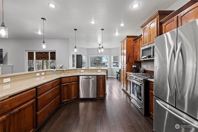 kitchen with pendant lighting, sink, dark wood-type flooring, appliances with stainless steel finishes, and light stone counters