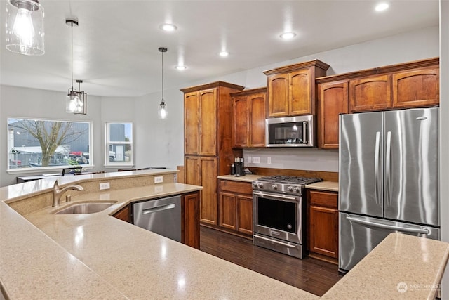 kitchen with dark wood-type flooring, sink, hanging light fixtures, appliances with stainless steel finishes, and light stone countertops