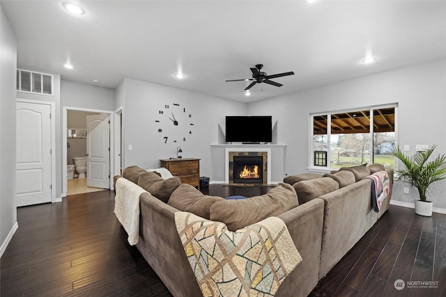 living room with dark wood-type flooring, ceiling fan, and a fireplace