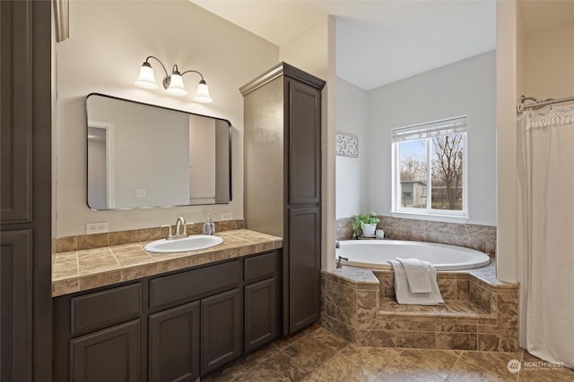 bathroom featuring vanity, vaulted ceiling, and tiled bath