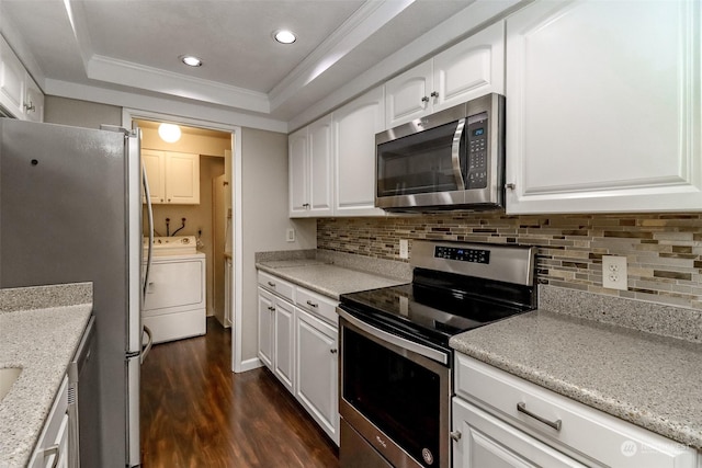 kitchen featuring a raised ceiling, white cabinetry, washer / clothes dryer, stainless steel appliances, and dark wood-type flooring