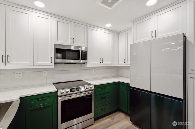 kitchen with light stone counters, appliances with stainless steel finishes, light hardwood / wood-style flooring, and white cabinets