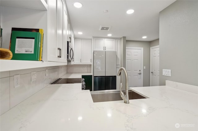 kitchen featuring white cabinetry, sink, white fridge, range, and light stone countertops