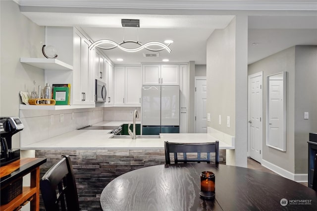 kitchen featuring white refrigerator, pendant lighting, and white cabinets