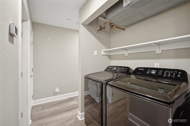 laundry area with light hardwood / wood-style flooring and washer and dryer