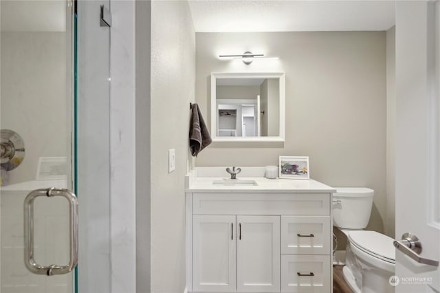 bathroom featuring walk in shower, vanity, and toilet