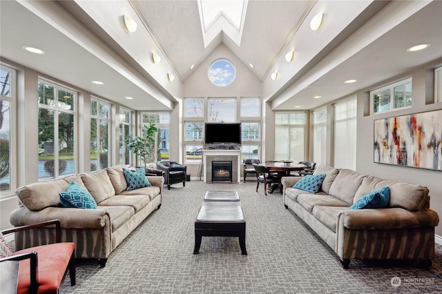 carpeted living room featuring a fireplace, a skylight, and high vaulted ceiling