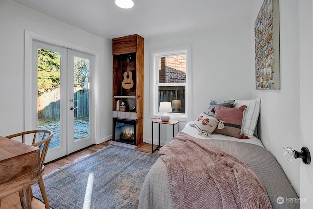 bedroom with french doors, a large fireplace, access to exterior, and light wood-type flooring